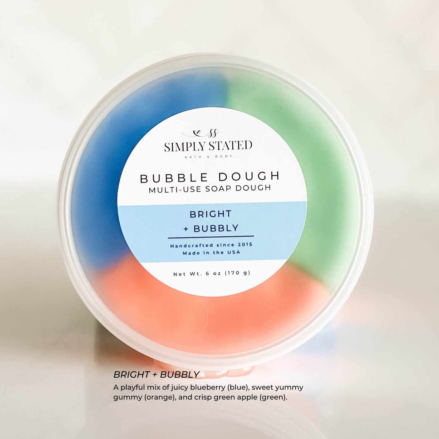Simply Stated Bubble Dough in Bright + Bubbly scent, a colorful multi-use soap dough in blue, green, and orange. Play, mold, and wash for a fun bath experience.