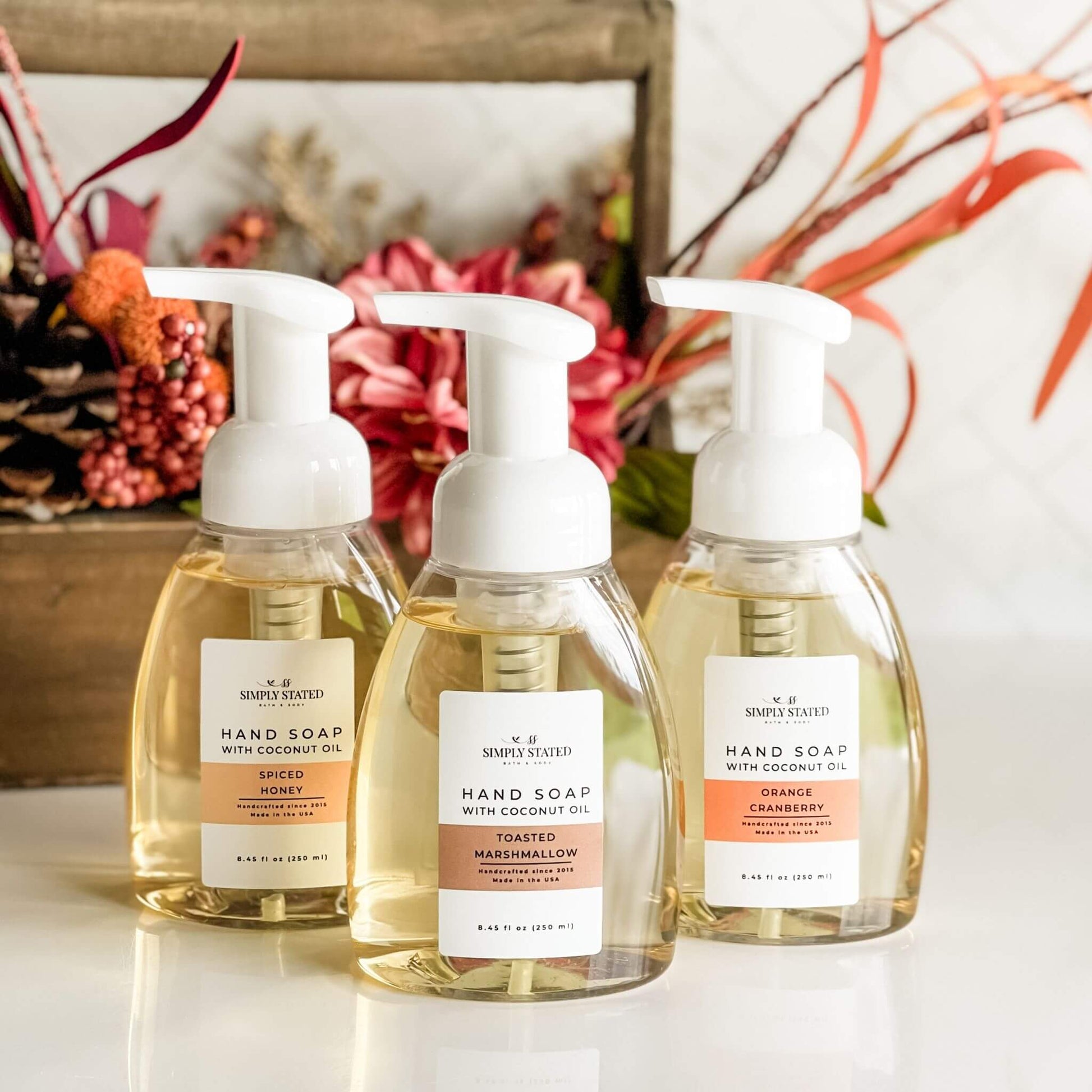 Simply Stated Fall Foaming Hand Soap in Orange Cranberry, Spiced Honey, and Toasted Marshmallow with floral fall background