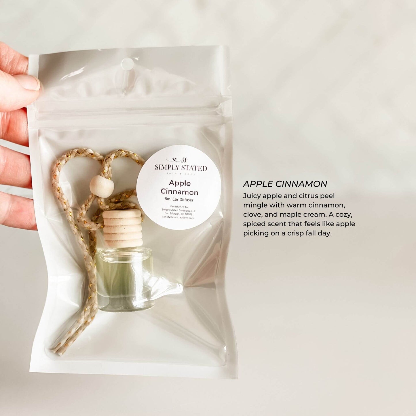 Apple cinnamon-scented diffuser packaging held by a hand on a light background