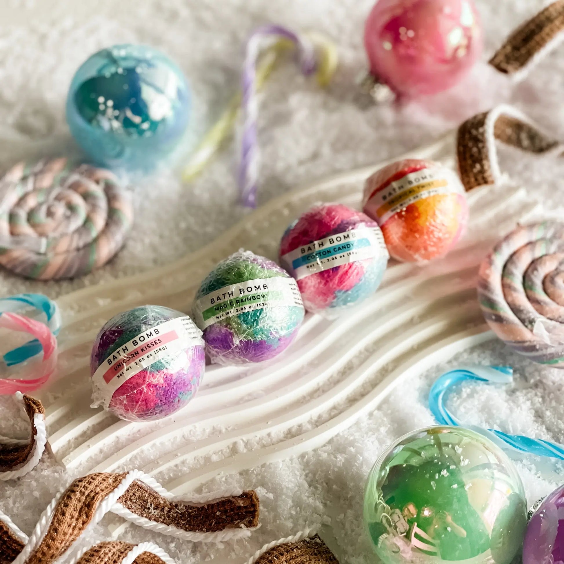 Colorful bath bombs with decorative ribbons on a white surface
