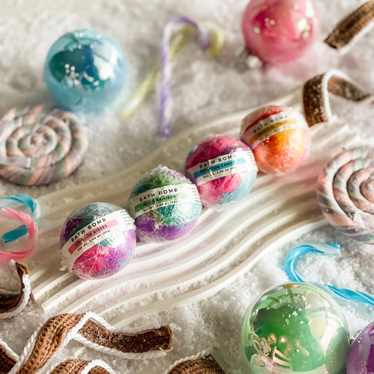 Colorful bath bombs with decorative ribbons on a white surface