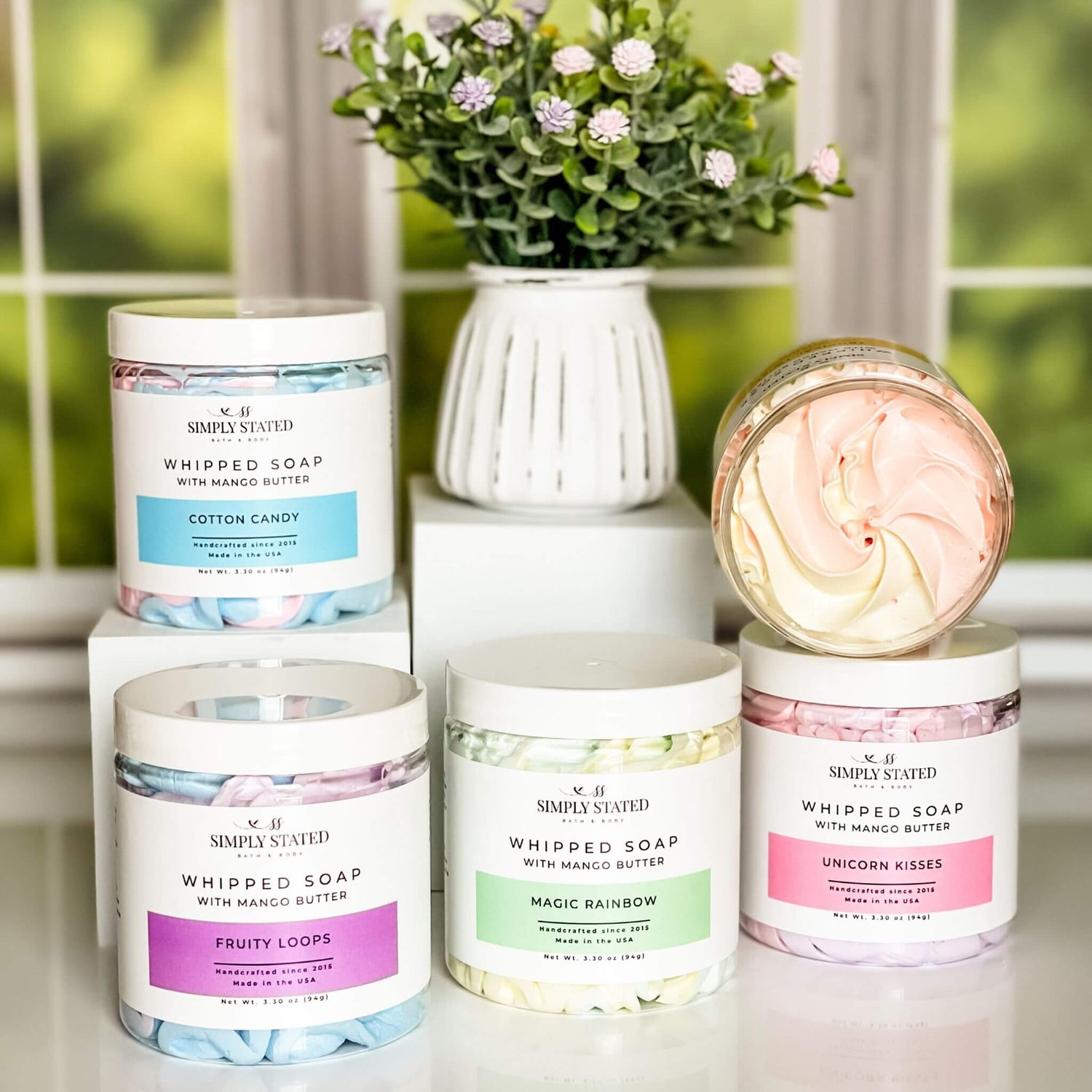 A collection of Simply Stated Bath & Body's Kids Whipped Soap in fun, vibrant swirls, featuring Cotton Candy, Fruity Loops, Magic Rainbow, Tropical Twist, and Unicorn Kisses.