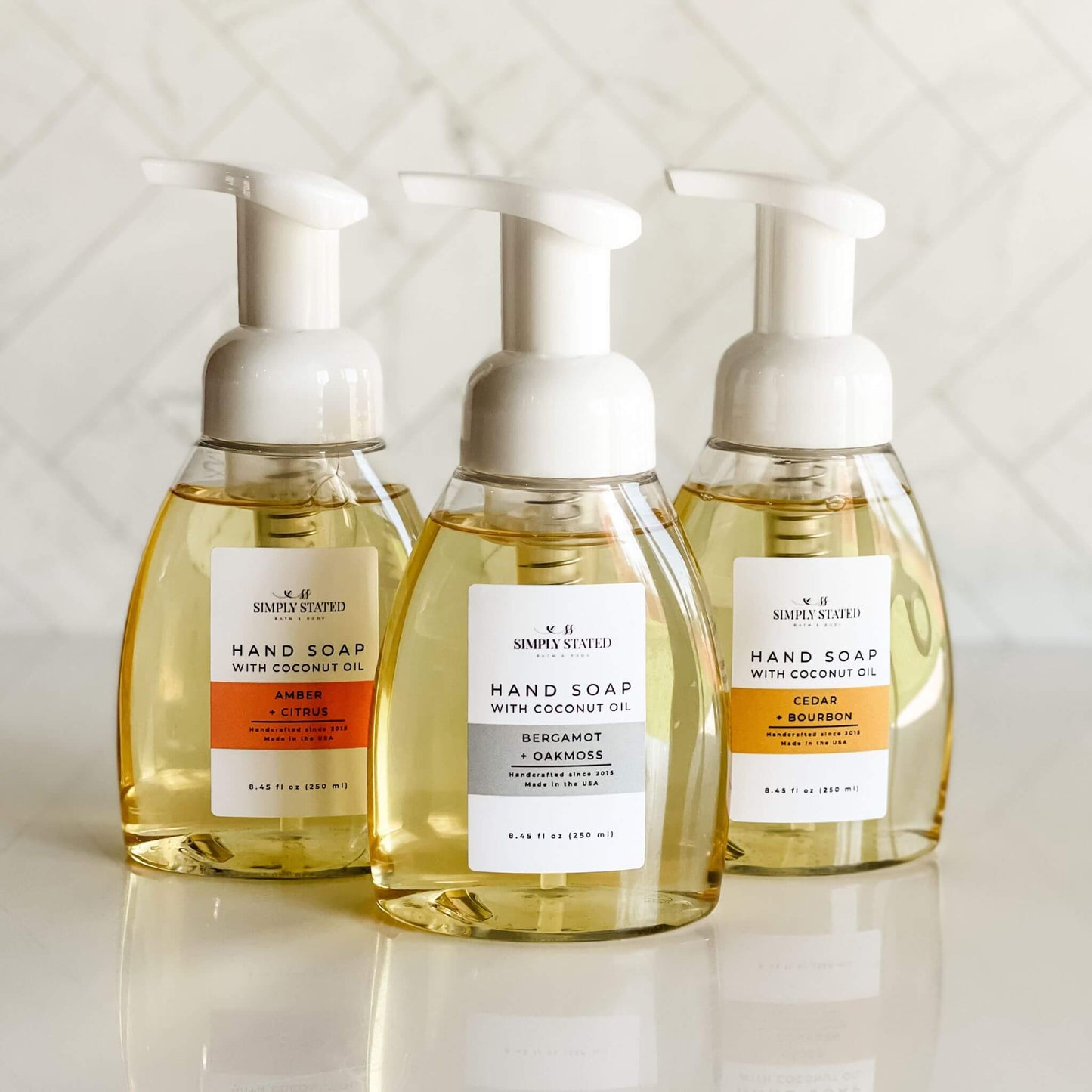 Three bottles of hand soap with different scents on a light background