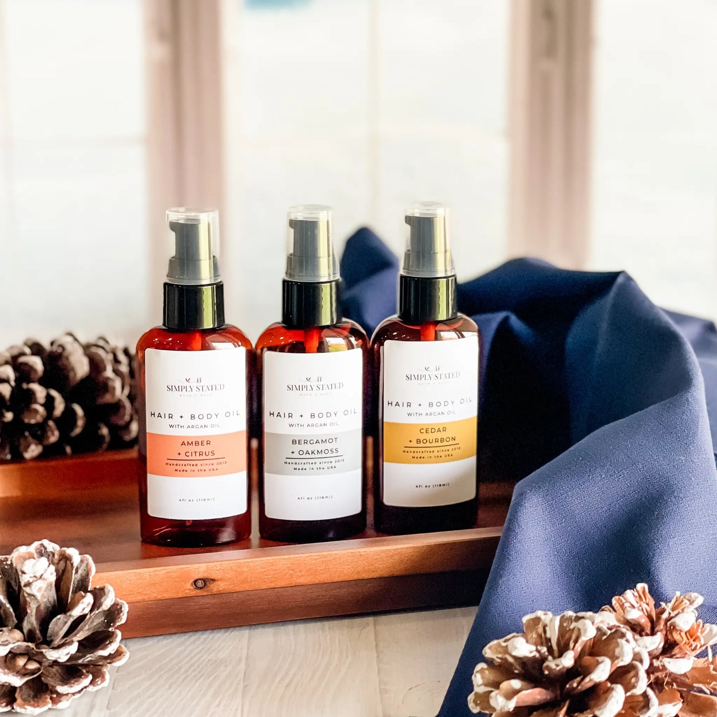 Three bottles of 'Simply Skincare' products on a wooden tray with decorative pinecones.
