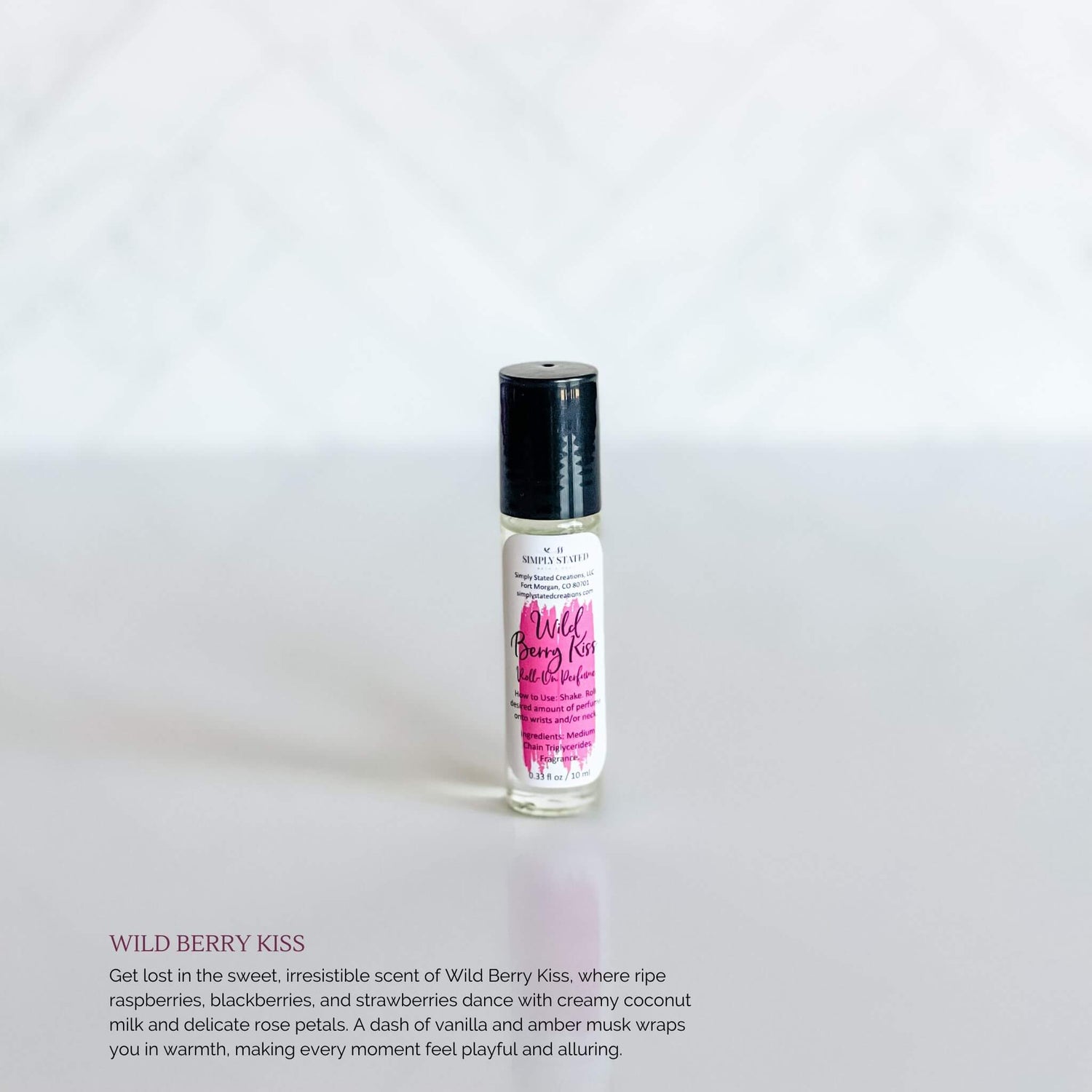 Simply Stated Bath & Body Wild Berry Kiss Roll-On Perfume in a clear glass bottle with a magenta label and black cap, displayed on a crisp white background.