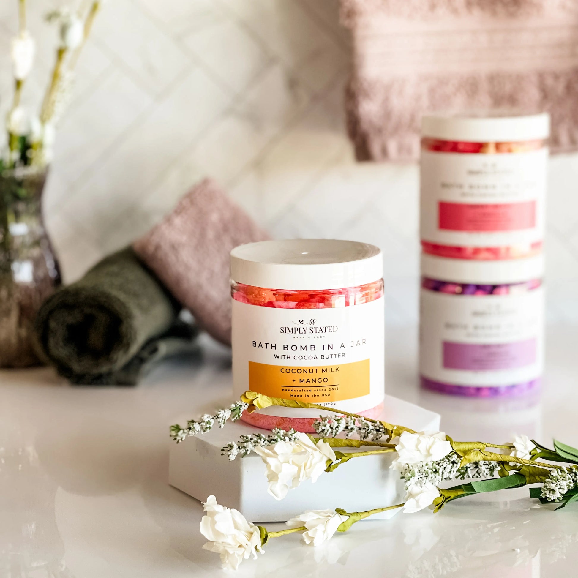 Bath bomb in a jar with decorative flowers on a marble surface