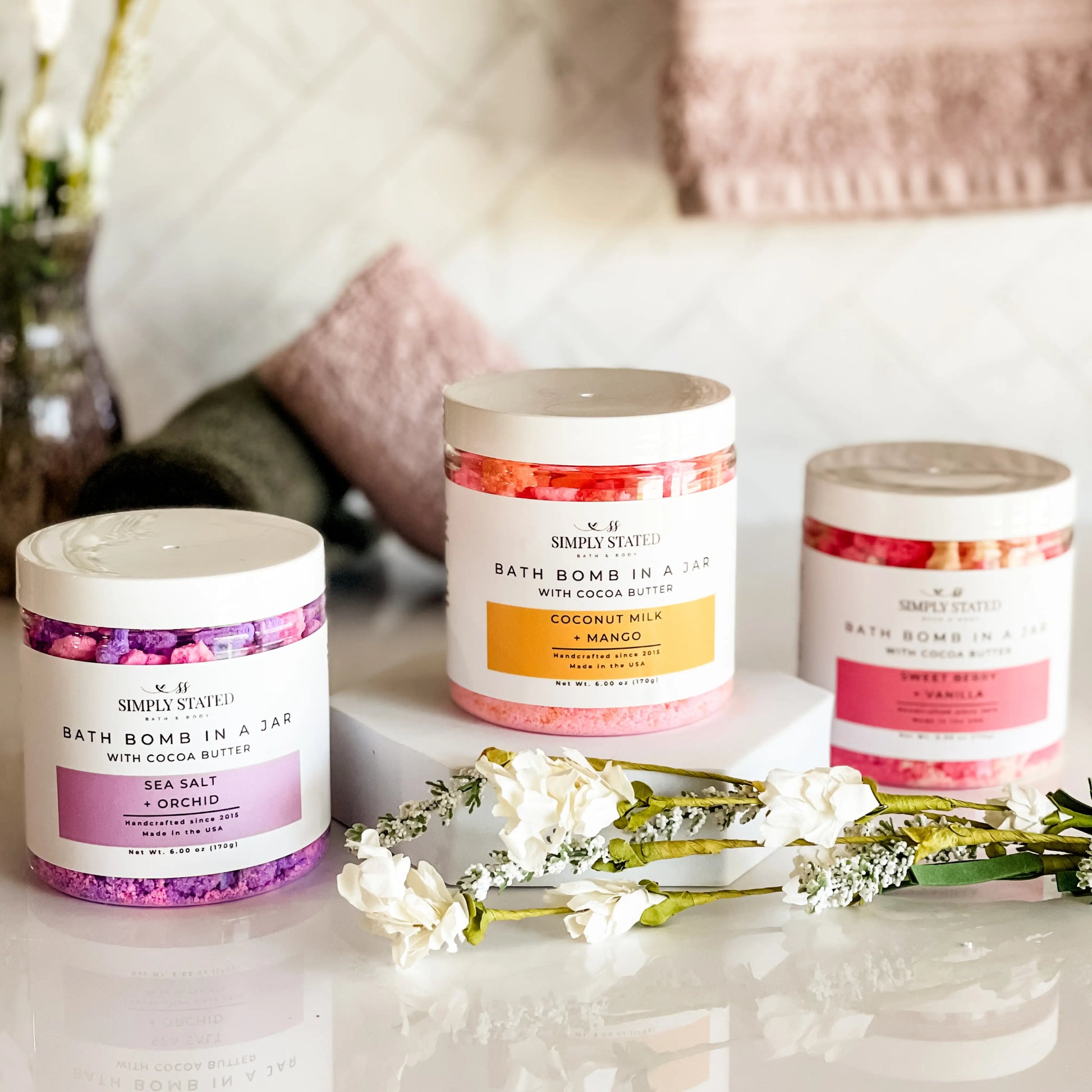 Three bath bomb jars with decorative elements on a surface