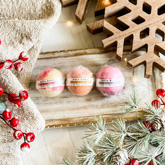 Three bath bombs on a wooden board with Christmas decorations