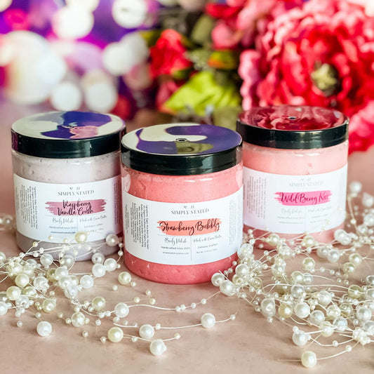 A trio of Sweet Temptations Body Polishes—Raspberry Vanilla Crush, Strawberry Bubbly, and Wild Berry Kiss—arranged with pearl accents on a blush pink background and vibrant floral decor.