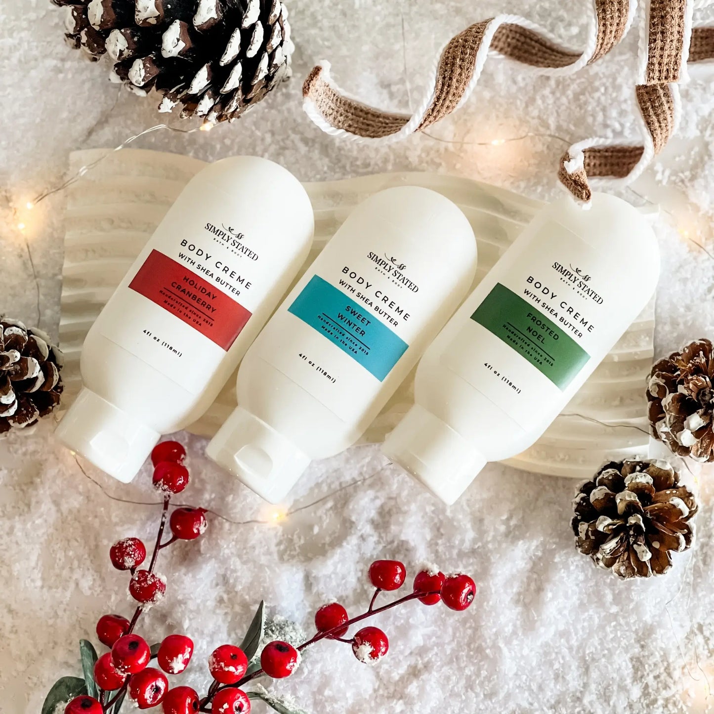 Three bottles of body cream with decorative elements on a textured surface