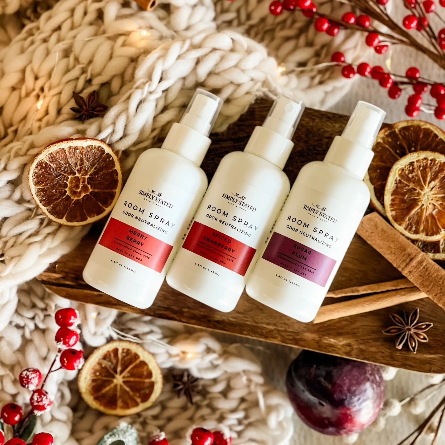 Three bottles of room spray on a wooden tray with decorative elements.