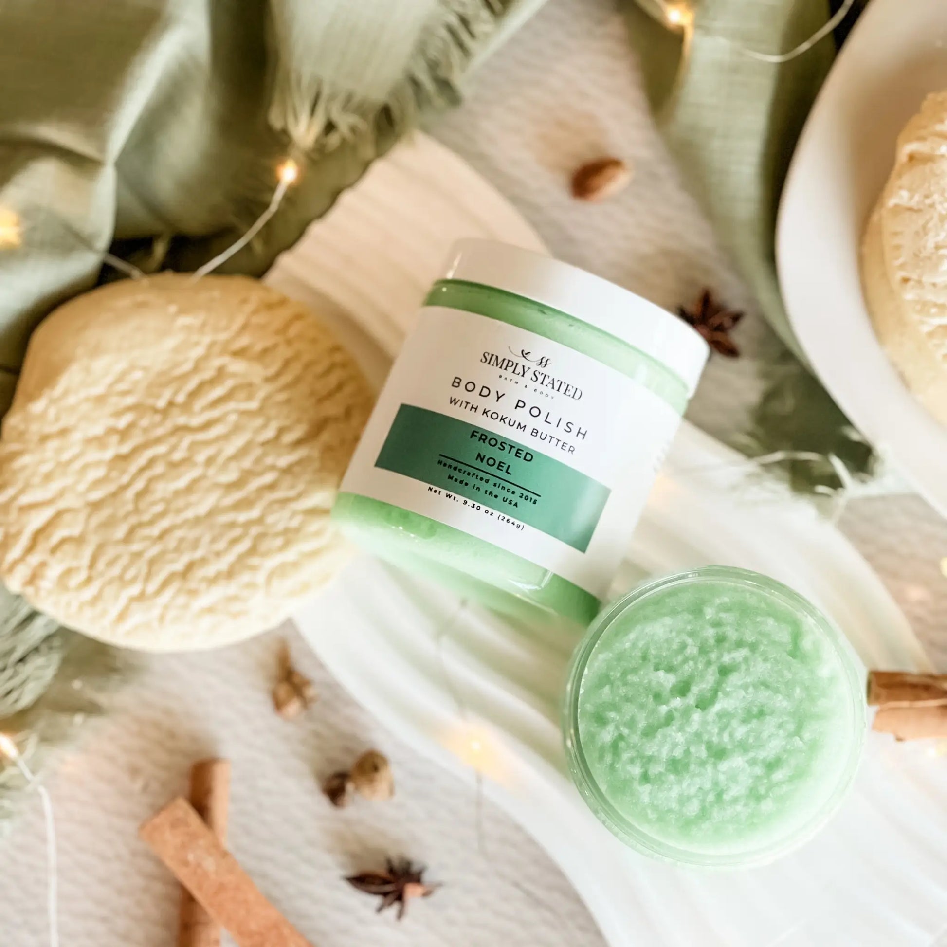 Green body polish jar with a scoop of product on a decorative background