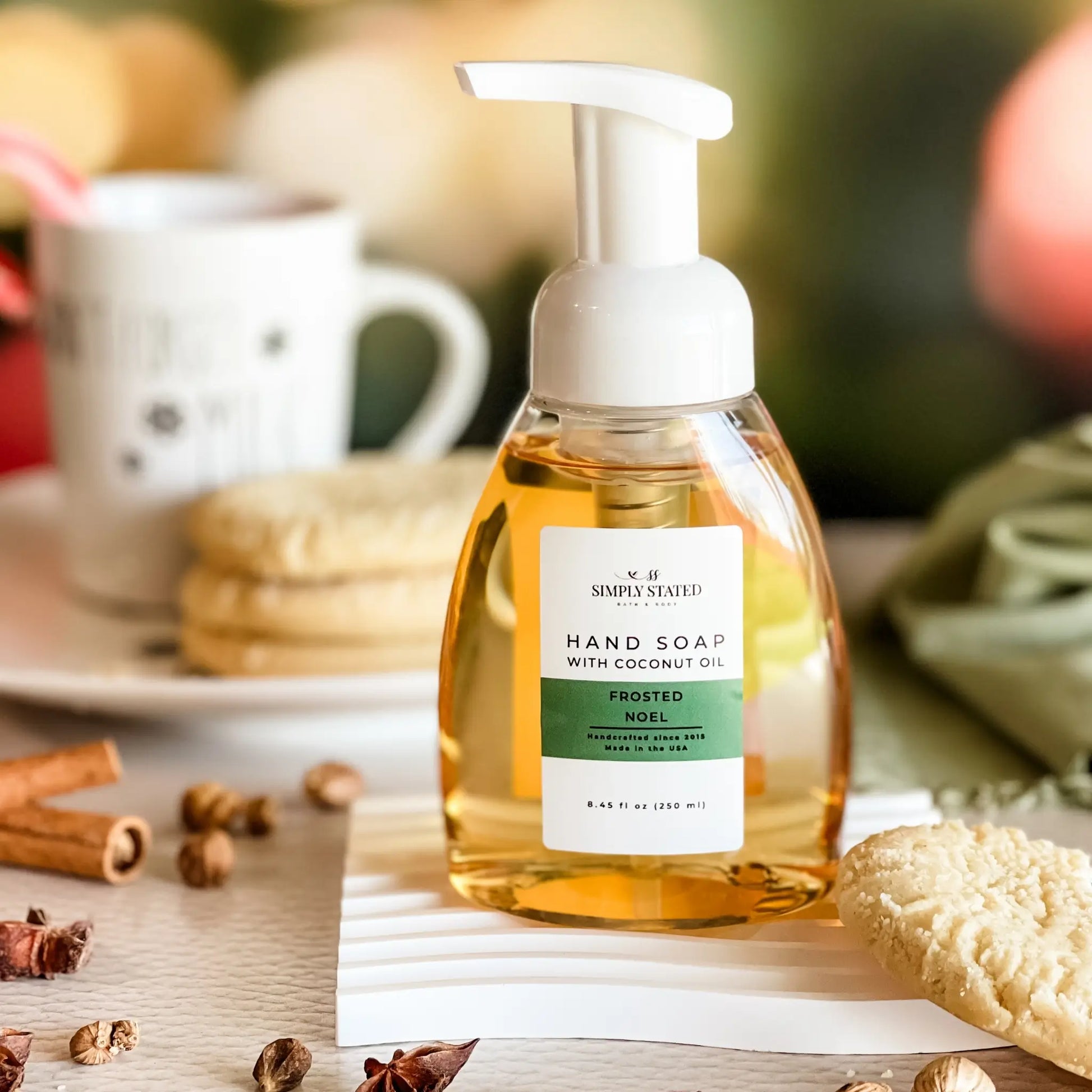 Hand soap bottle with a label on a table with cookies and cinnamon sticks