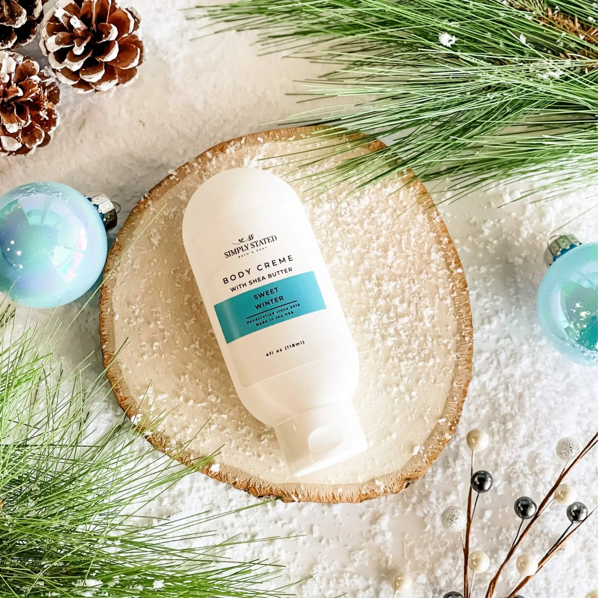 Body cream bottle on a wooden plate with Christmas decorations and greenery