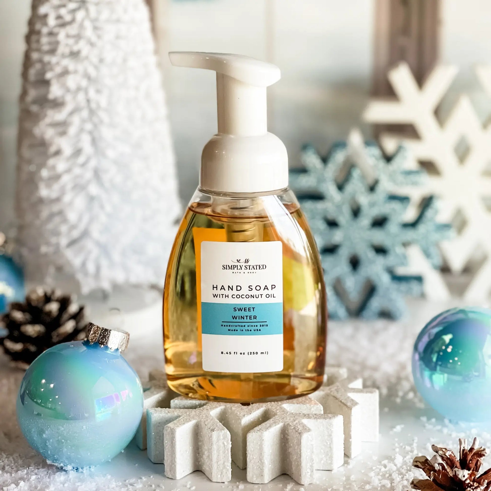 Hand soap bottle with decorative Christmas elements on a snowy background