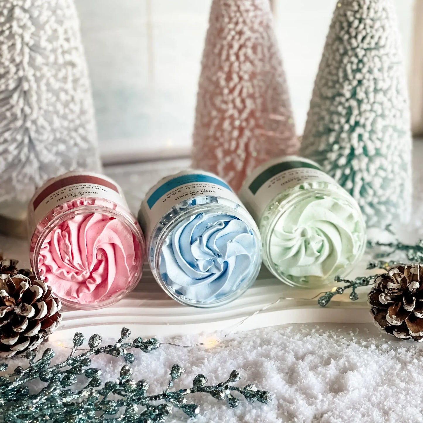 Three containers of whipped cream with Christmas-themed decorations