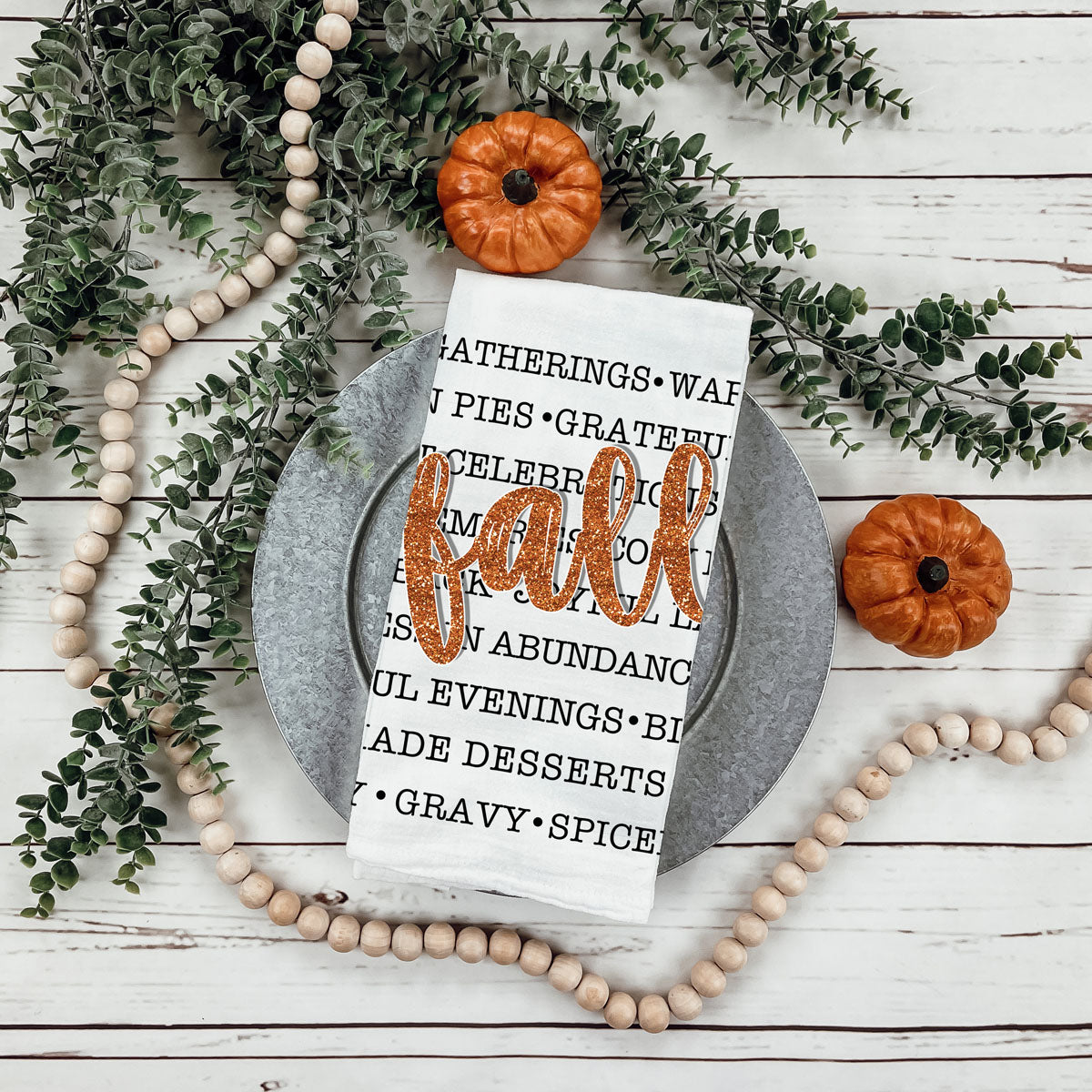 fall words towel used as backdrop for thanksgiving desserts
autumn text dish towel with black fonts and bold script
fall kitchen cloth featuring list of seasonal comforts
autumn cozy sayings towel beside copper cookware