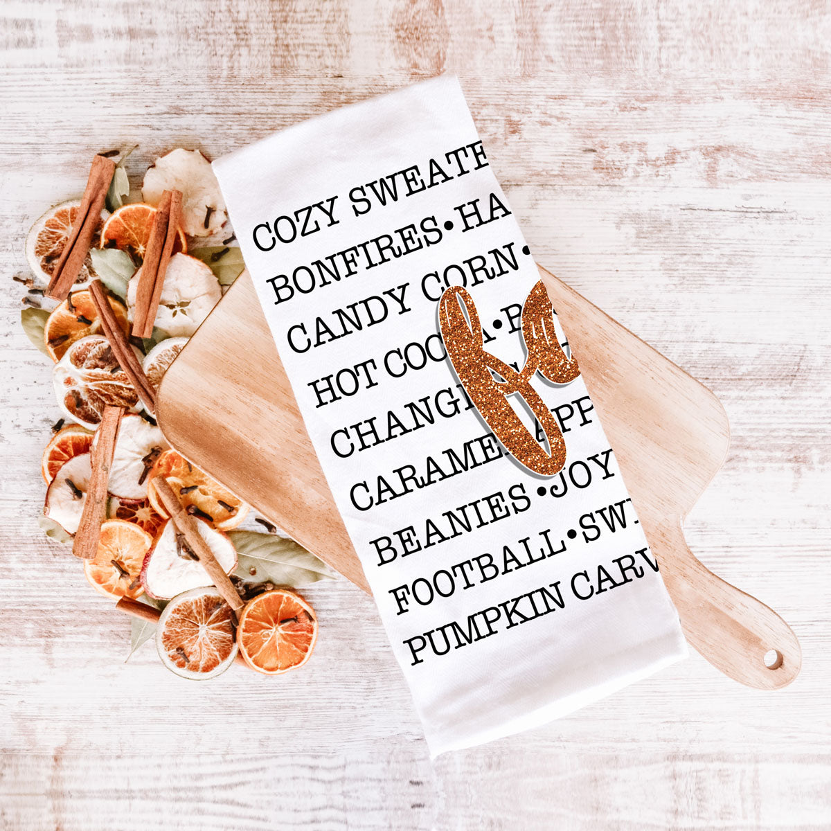 white cotton towel with black fall words and glitter script
modern farmhouse fall kitchen towel on cutting board
cozy fall sayings kitchen towel on white background
autumn word art tea towel with orange glitter fall text